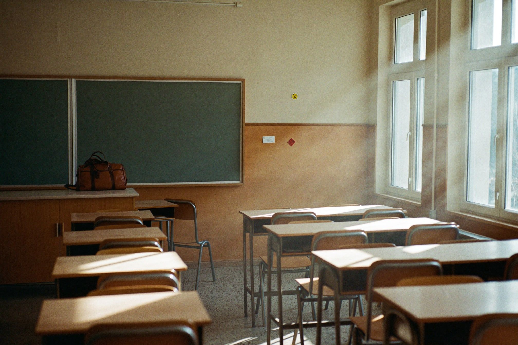Leeres Klassenzimmer am Nachmittag, auf dem Pult eine Lehrertasche